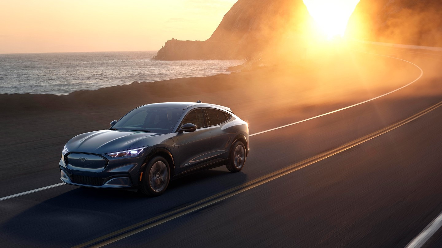 Ford Mach-E driving seaside road in sun set