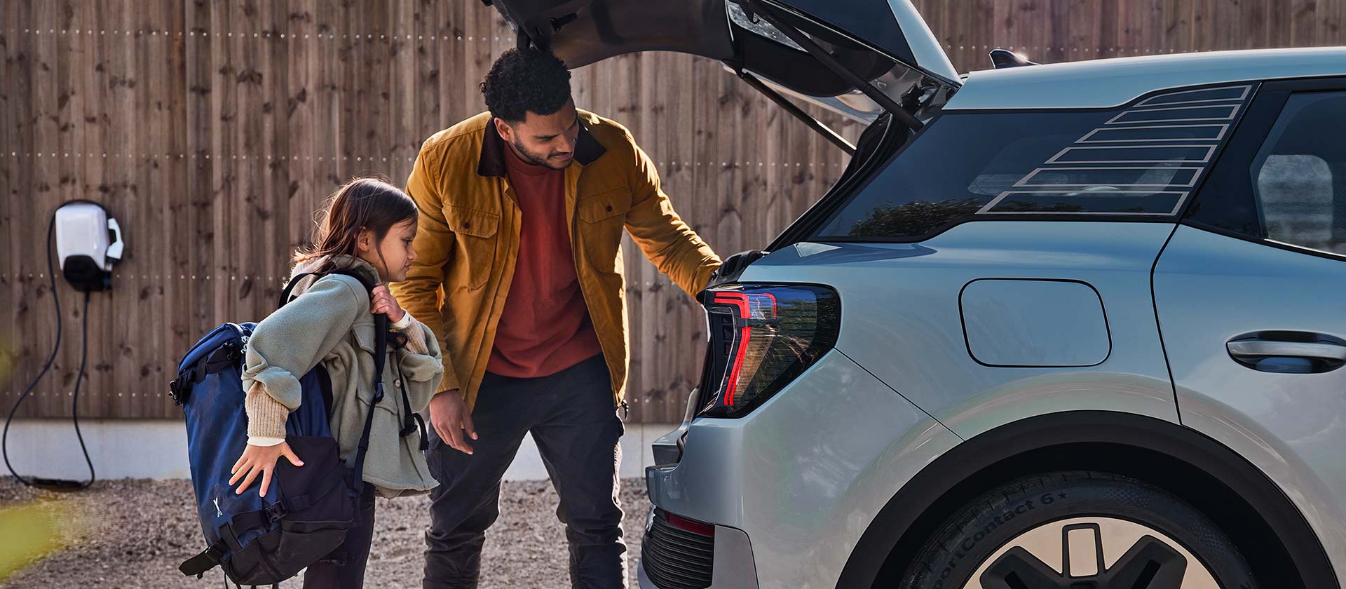 O familie care încarcă portbagajul unui Ford Explorer electric albastru.