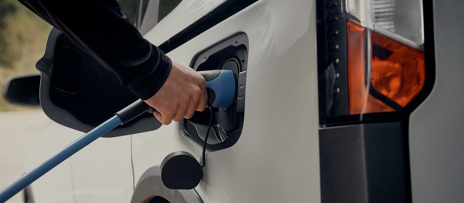 Prim-plan al unui vehicul electric Ford alb care este conectat la un încărcător EV.