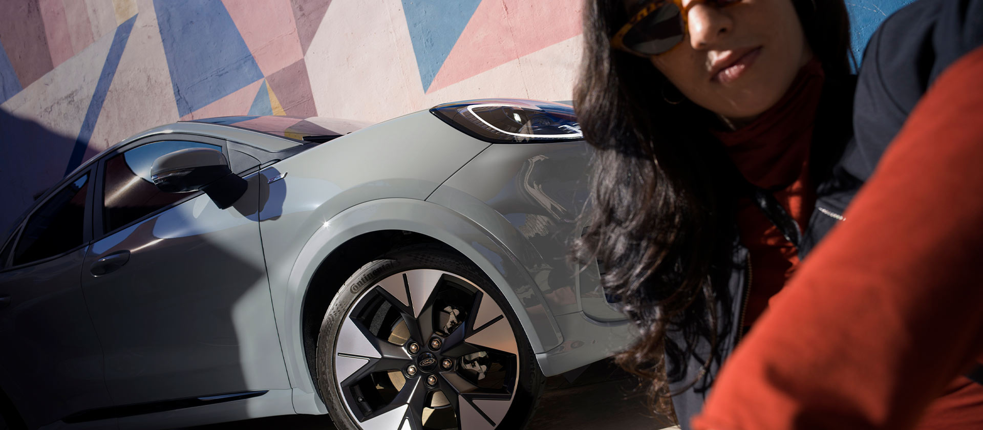 O persoană care stă lângă o mașină Ford Puma mild hybrid argintie.
