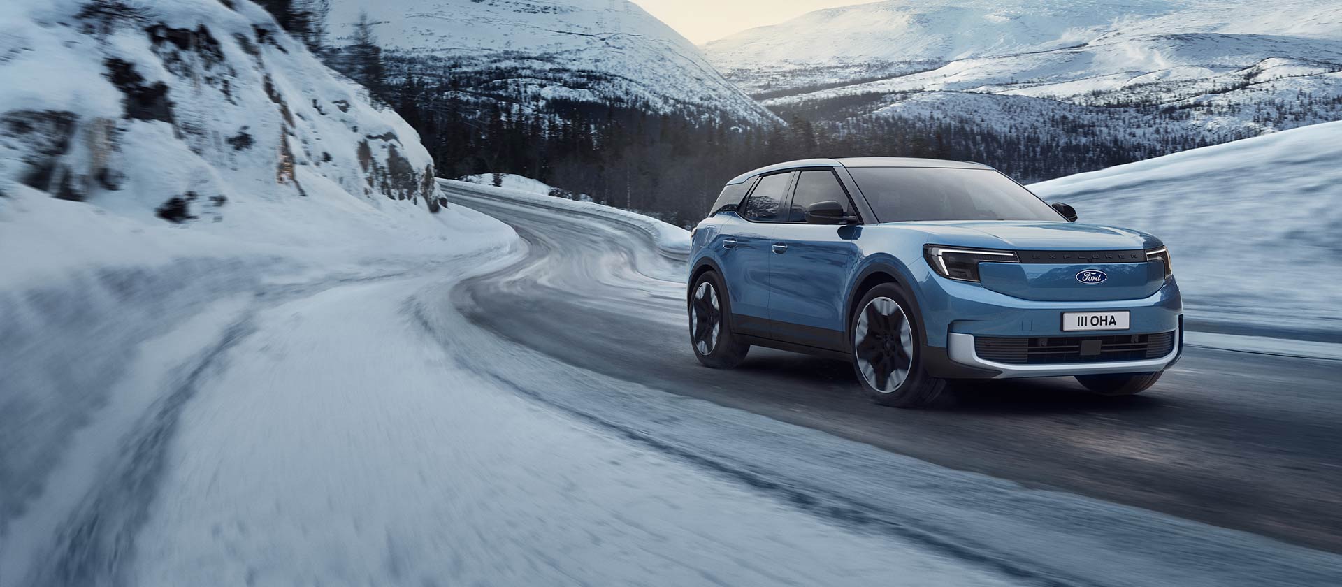 Ford Explorer electric albastru pe un drum montan înzăpezit, evidențiind capacitatea și autonomia în condiții de iarnă.