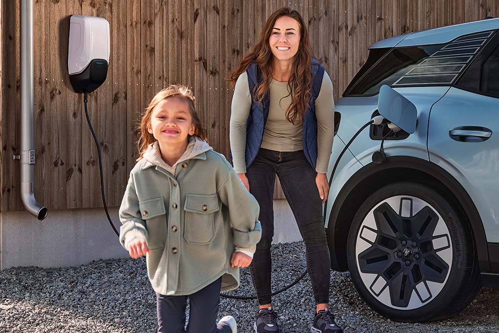 O familie care se distrează în timp ce își încarcă Ford Explorer electric acasă.