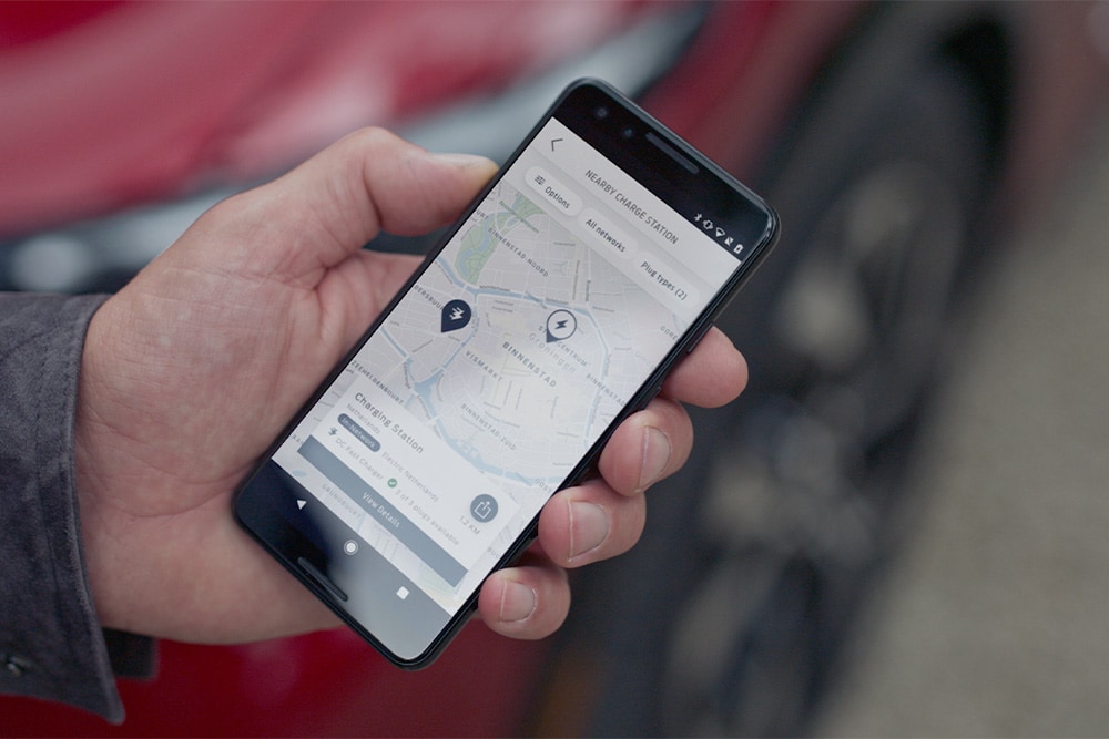 Un smartphone care afișează aplicația FordPass™ cu puncte de încărcare din apropiere pentru încărcarea publică Ford EV.