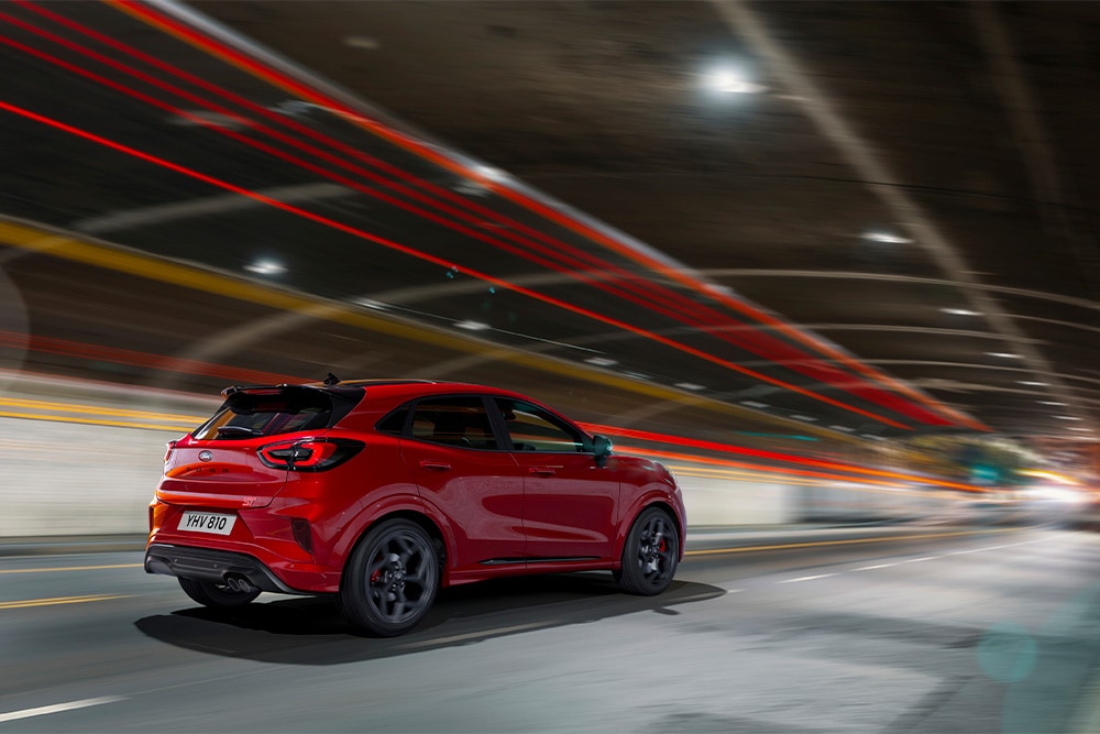 O mașină Ford Focus mild hybrid roșie care conduce printr-un tunel.