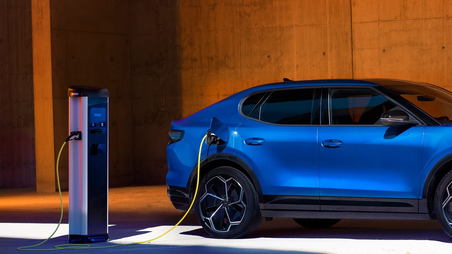 Un vehicul electric Ford Capri albastru conectat la un încărcător EV.