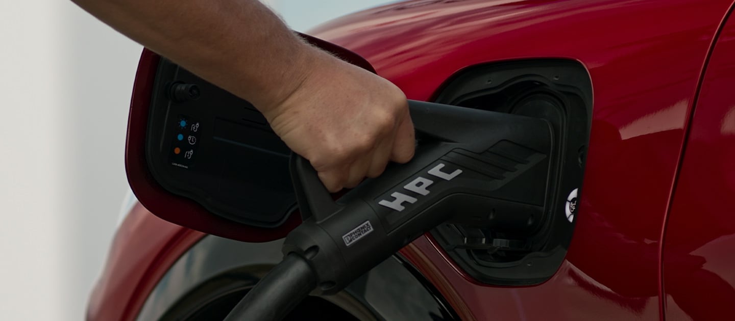 Prim-plan al unui Ford EV roșu conectat la un HPC public (încărcător de mare putere), pentru încărcare rapidă a vehiculelor electrice publice.