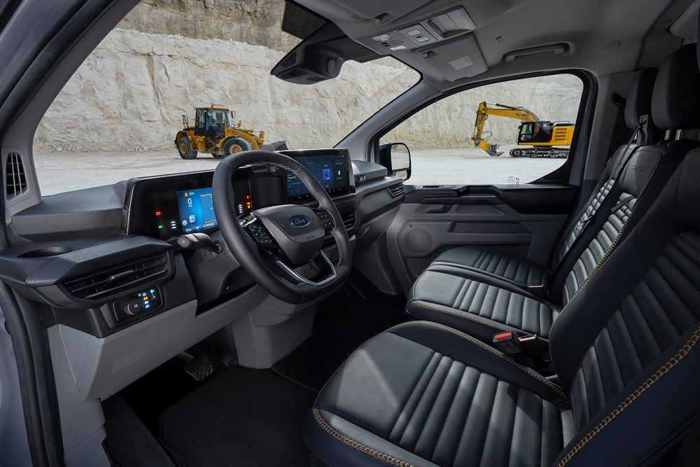 Interiorul unei autoutilitare electrice Ford E-Transit Custom, cu scaunele și volanul vizibile, parcată într-o carieră. 