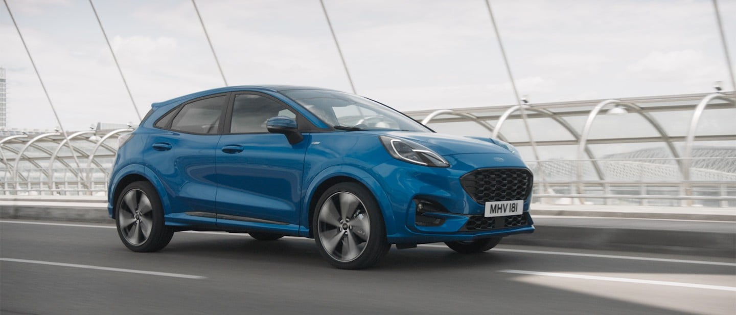 Blue Ford Puma driving on bridge side view