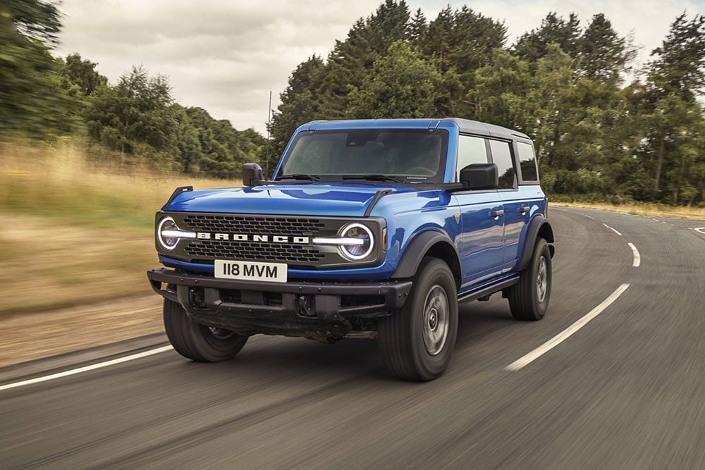 Vedere frontală a modelului Ford Bronco în culoarea albastră, deplasându-se pe un drum de țară.