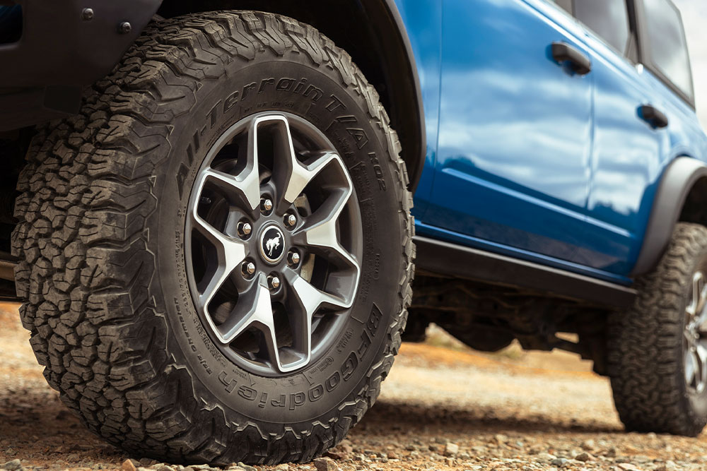 Prim-plan cu anvelopele all- terrain ale unui model Ford Bronco albastru.