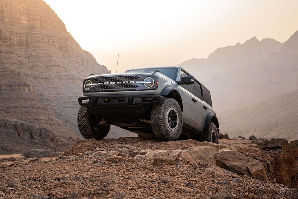 Un model Ford Bronco gri parcat pe o cărare stâncoasă într-un cadru montan.