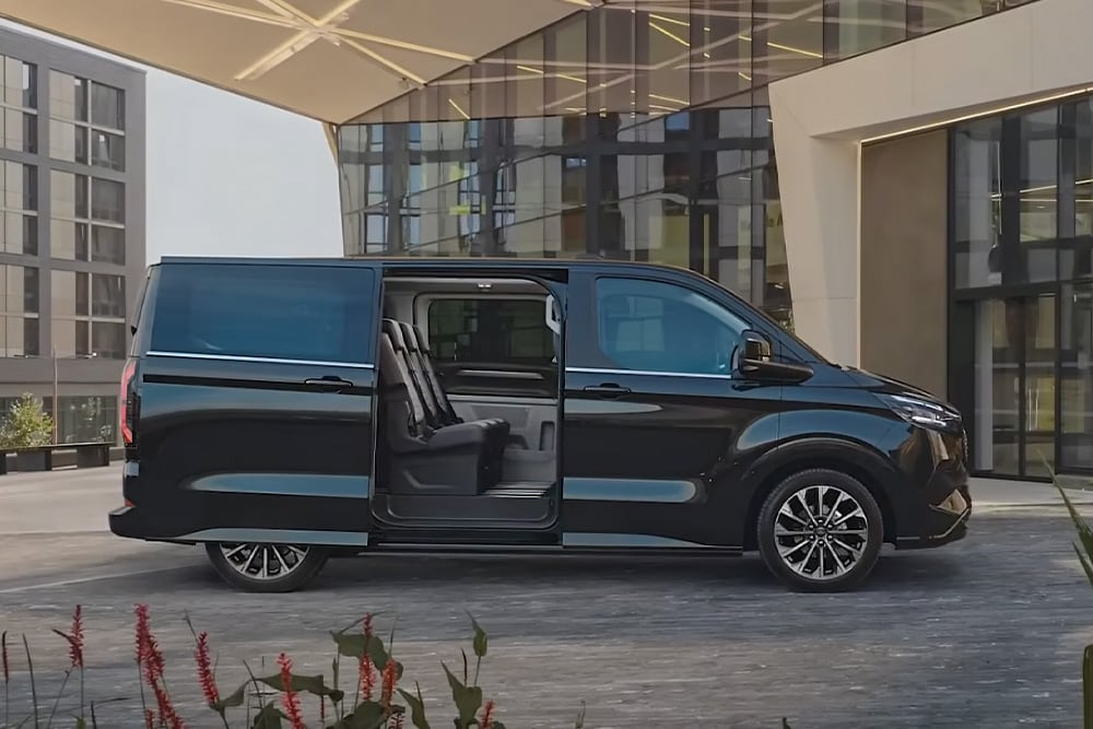 Un Ford E-Tourneo Custom negru este parcat cu ușa laterală deschisă, dezvăluind scaunele interioare.