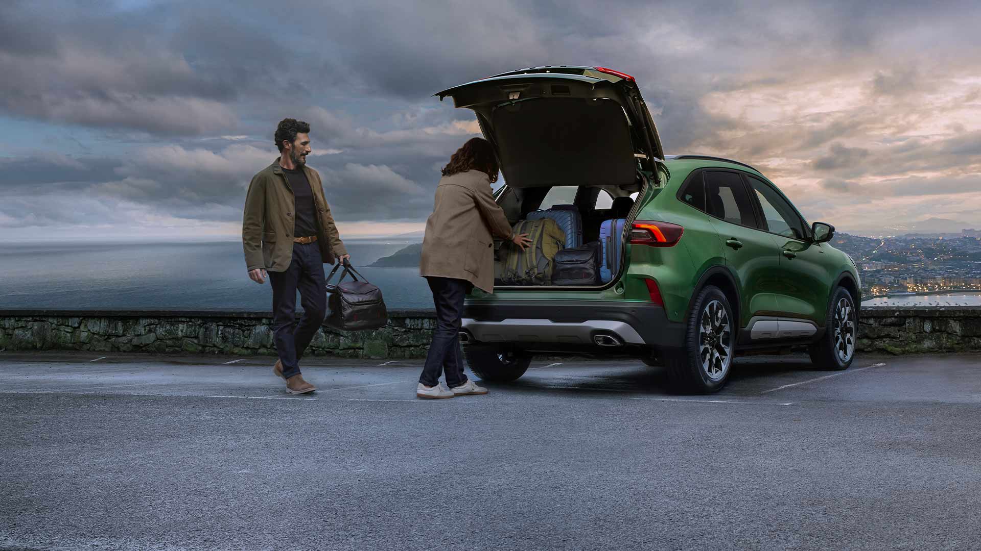 Two people loading multiple suitcases into the spacious Ford Kuga boot space.  