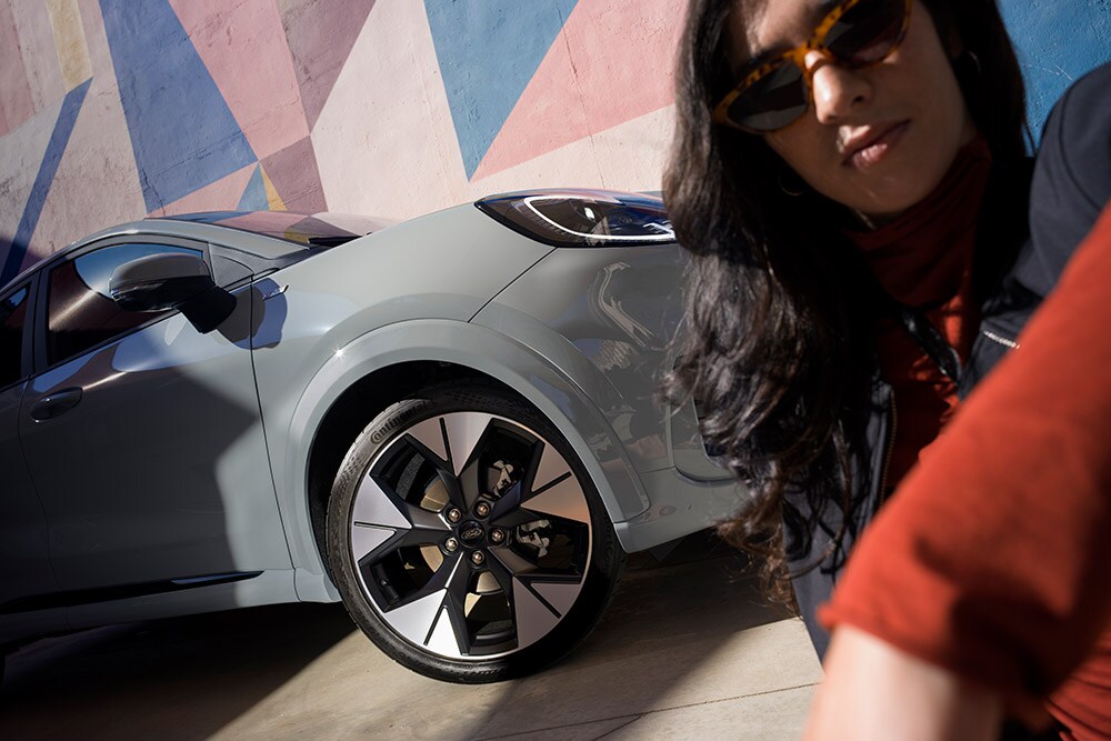 Prim-plan cu o persoană aflată lângă un vehicul Ford Puma® gri cu motor EcoBoost® pe benzină.