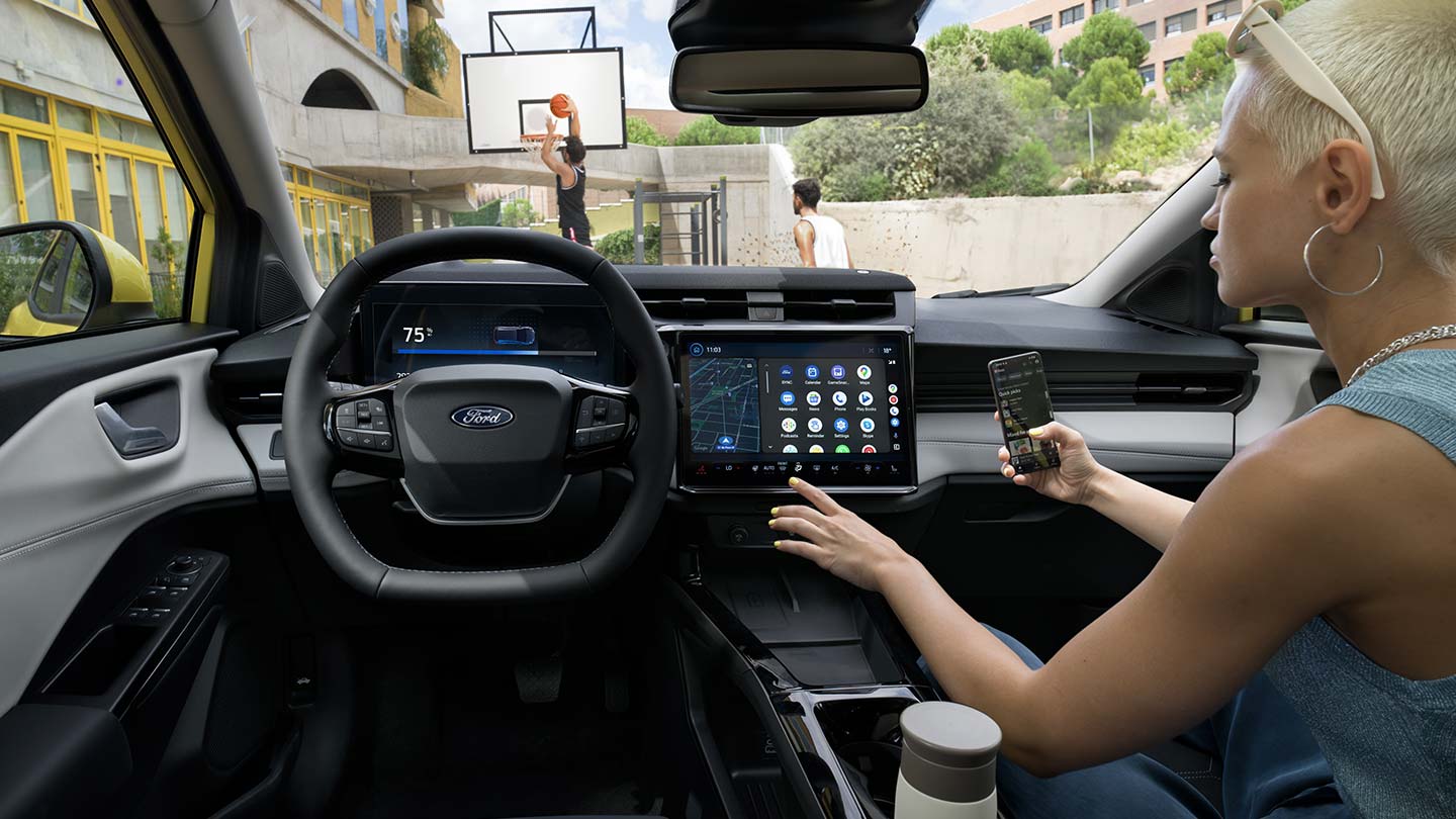 Interiorul modelului electric Ford Puma Gen-E®, cu o persoană care își sincronizează wireless telefonul cu ecranul tactil.