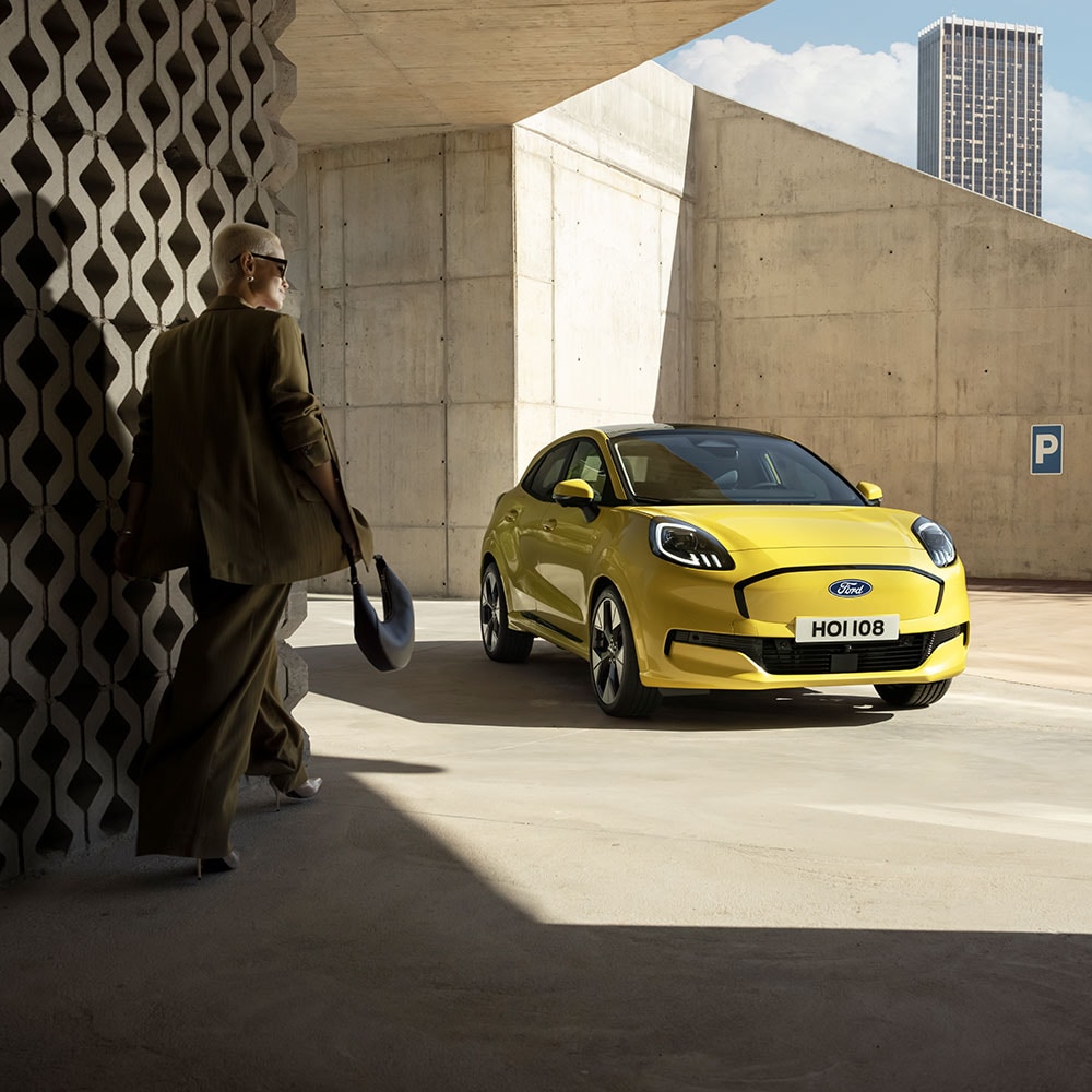 O persoană care se îndreaptă spre noul model Ford Puma Gen-E ® electric, de culoare galben.