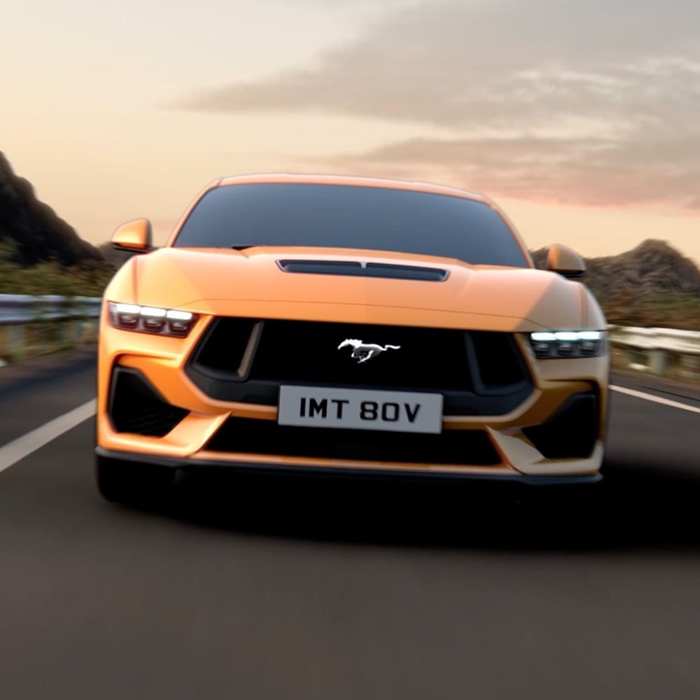 Vedere frontală a unui Ford Mustang portocaliu cu prim-plan pe faruri, grilă și sigla Mustang