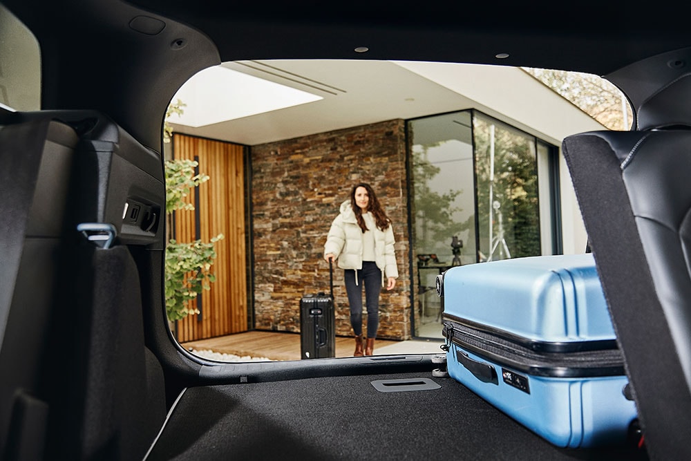 Imagine din interior a portbagajului modelului electric Ford Explorer, cu o geanta de voiaj albastră