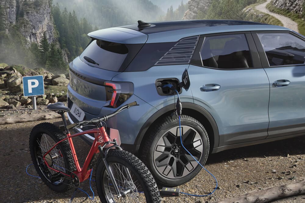 O bicicletă electrică ce se încarcă de la un Ford Explorer®, într-un peisaj montan pe fundal.