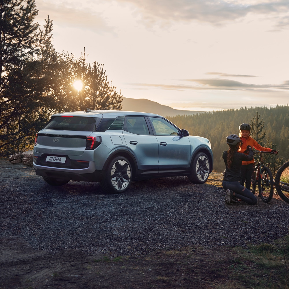 Ford Explorer parked with 2 people on bicycles