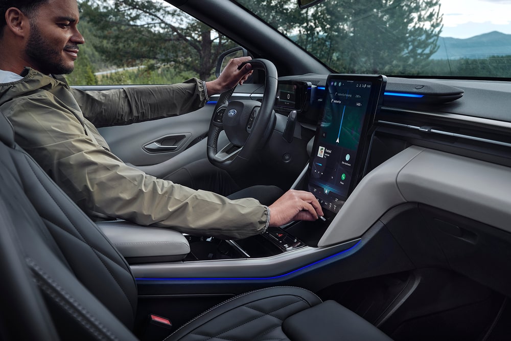 Șofer folosind sistemul de infotainment cu ecran tactil din interiorul modelului SUV Ford Explorer de familie.