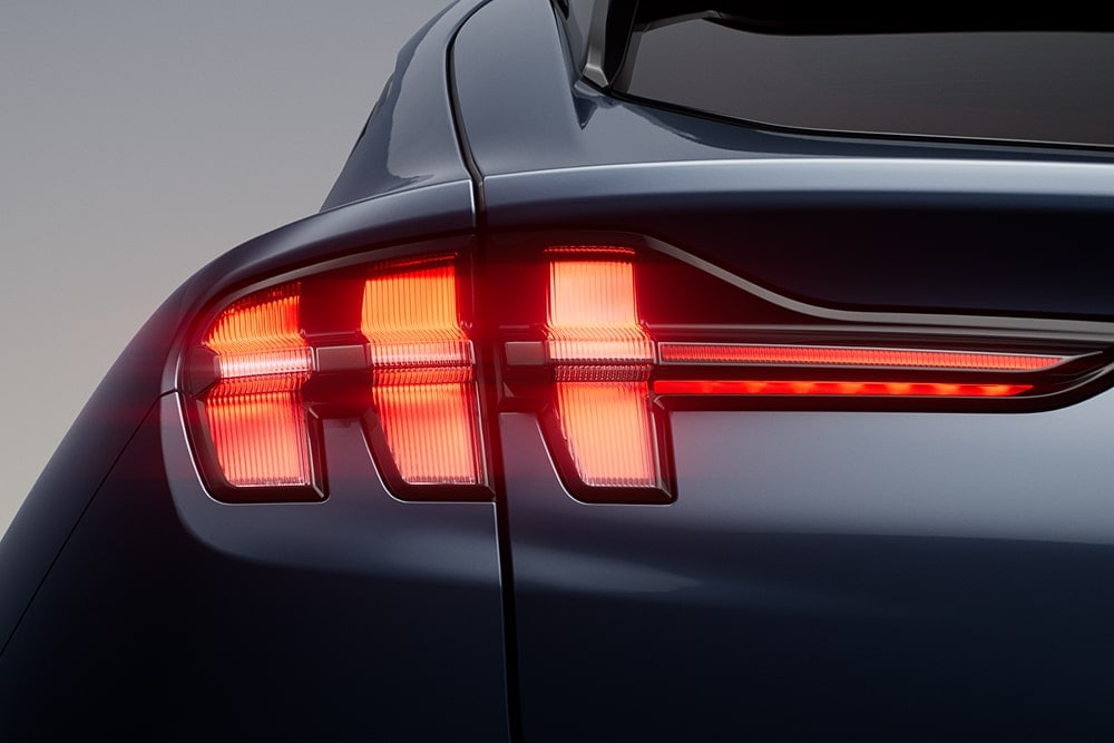 Prim-plan cu luminile triple spate iluminate ale unei mașini sport Ford Mustang Mach-E.
