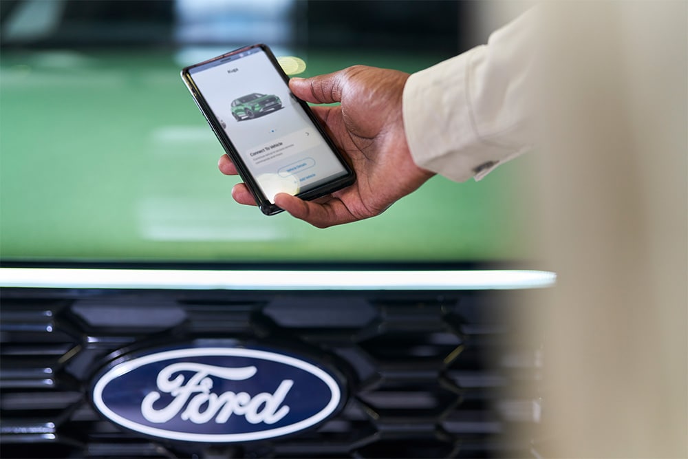 Bărbat care se uită la smartphone cu aplicația Ford afișată