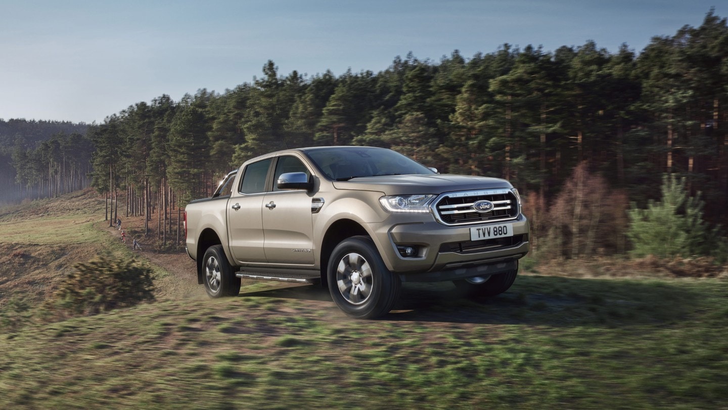 Ford Ranger on a grassy field near a forest 