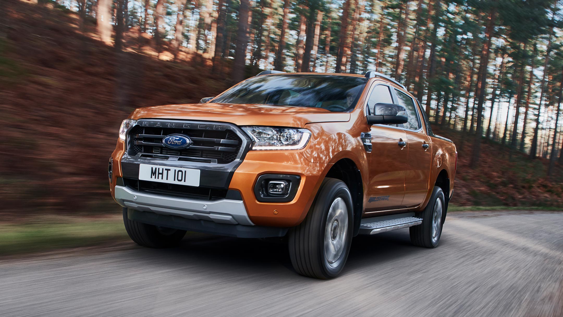 Ford Ranger Wildtrak portocaliu deplasându-se prin pădure, vedere din față, șapte optimi