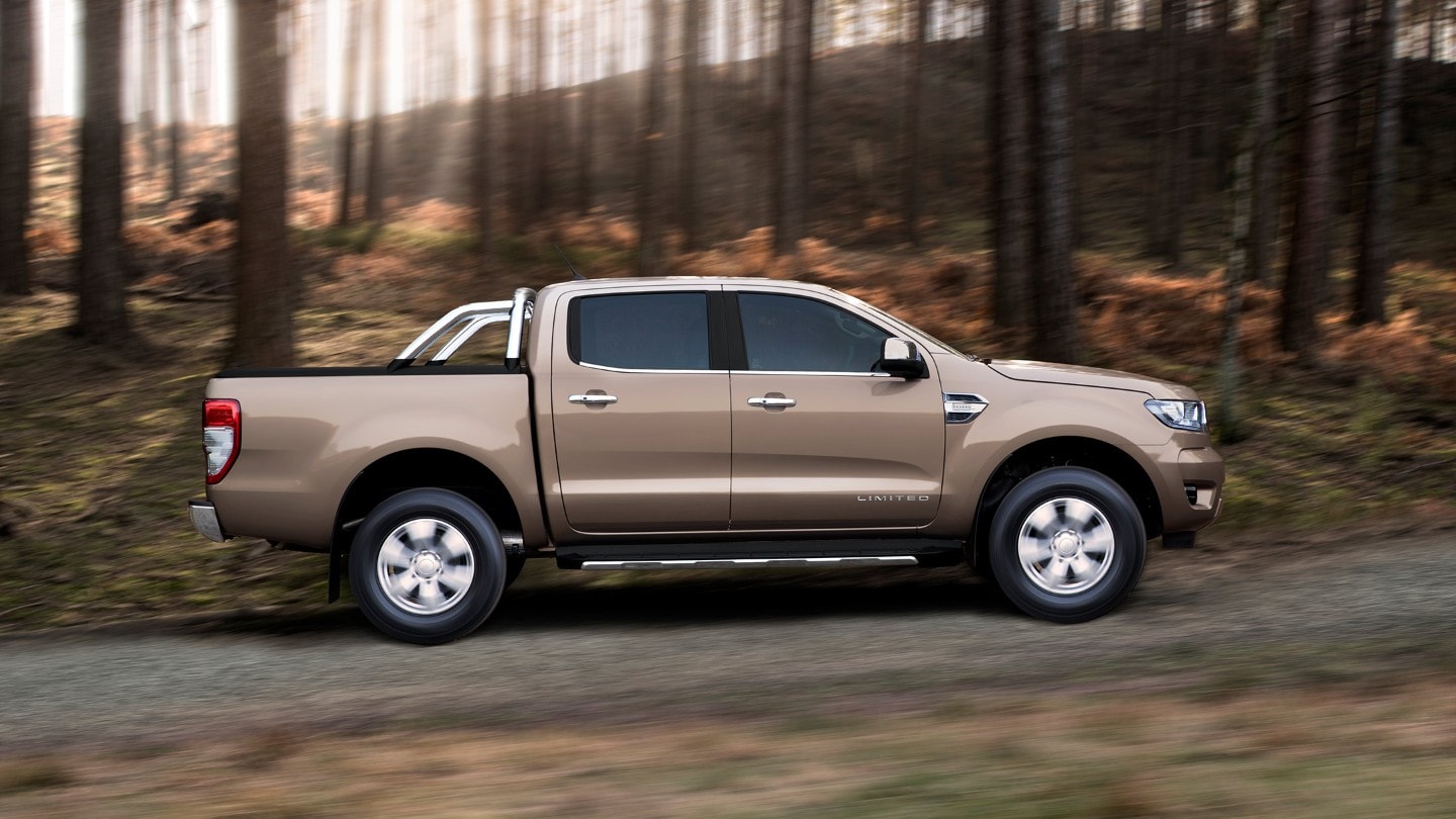 Ford Ranger Wildtrak argintiu parcat pe un drum forestier, vedere laterală