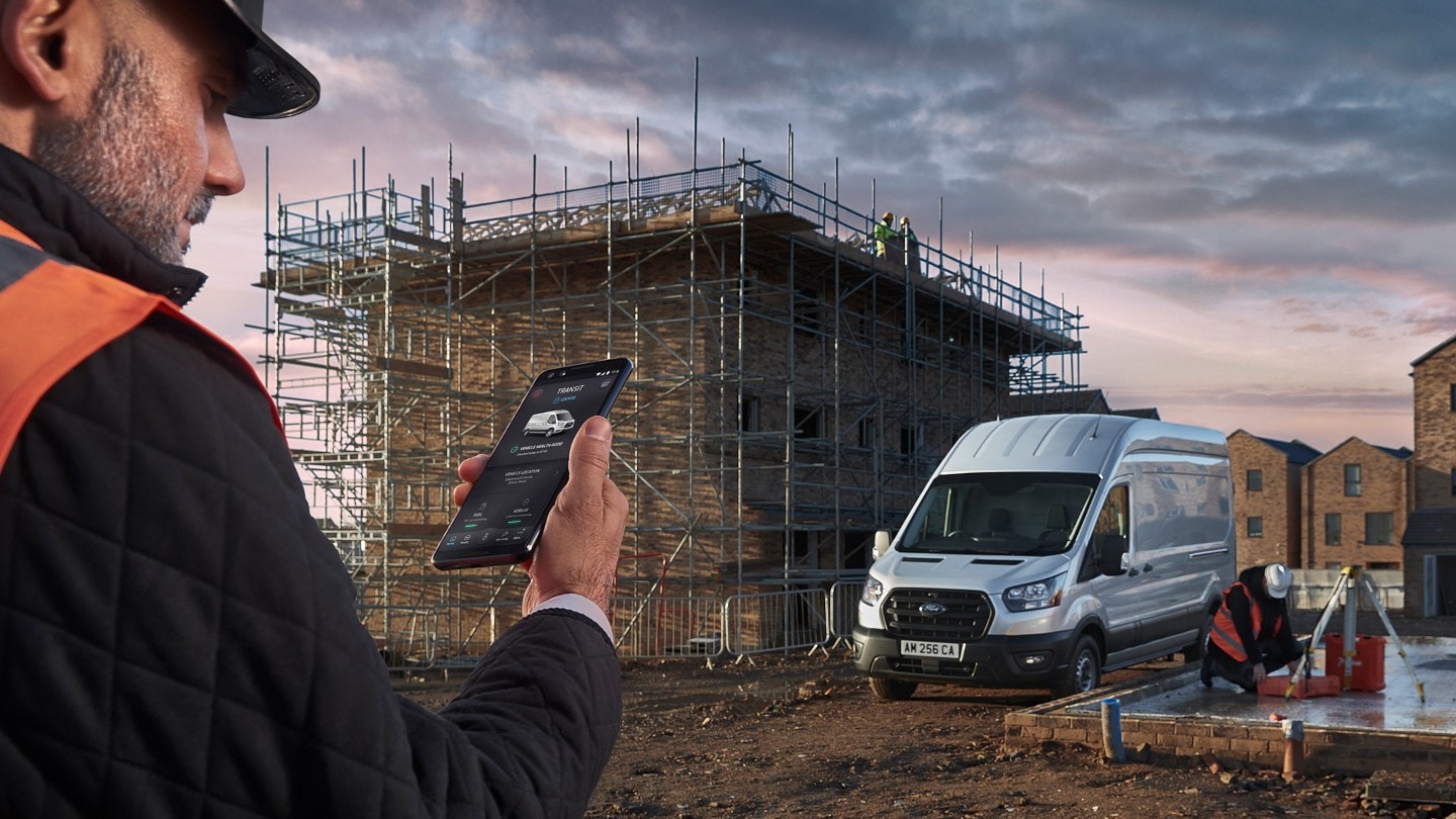 Man looking at his mobile phone on building site with Ford Transit