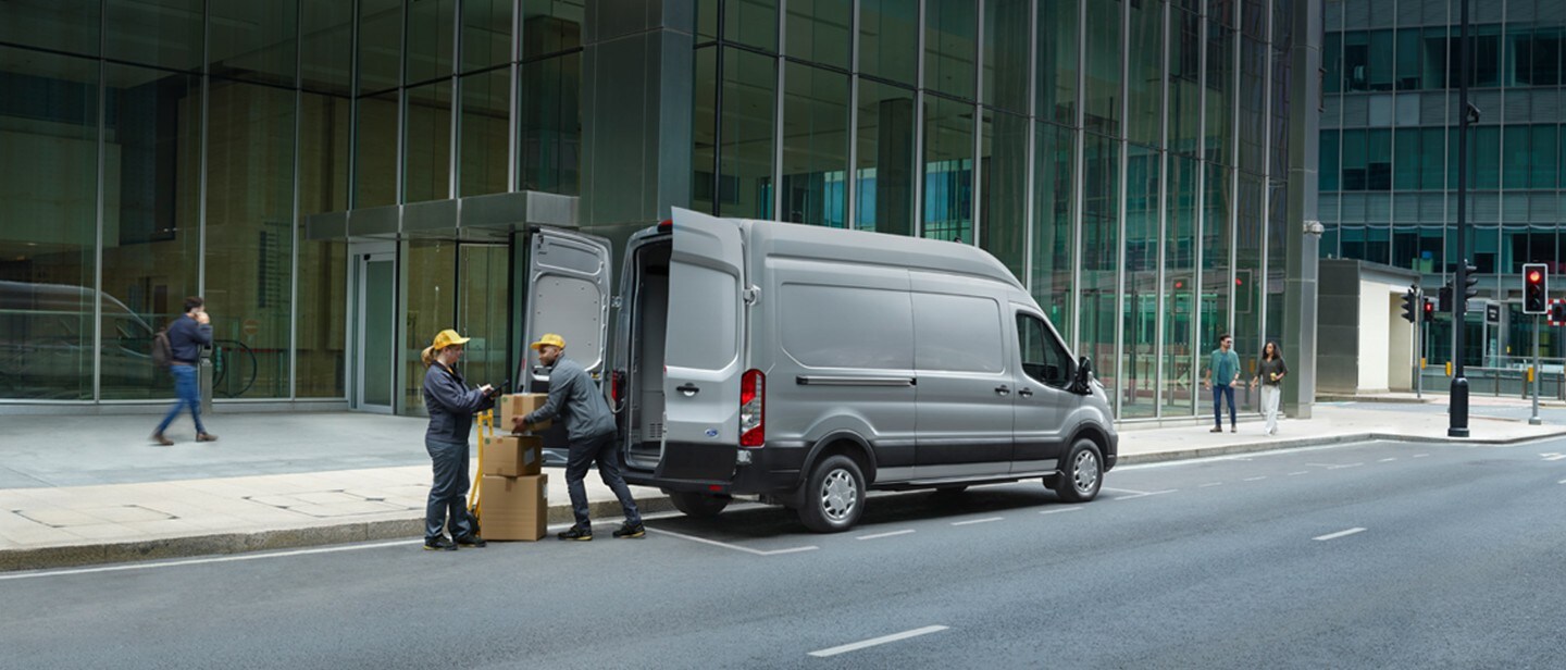 Noul Ford E-Transit cu livrator care încarcă cutii în vedere din spate 3/4