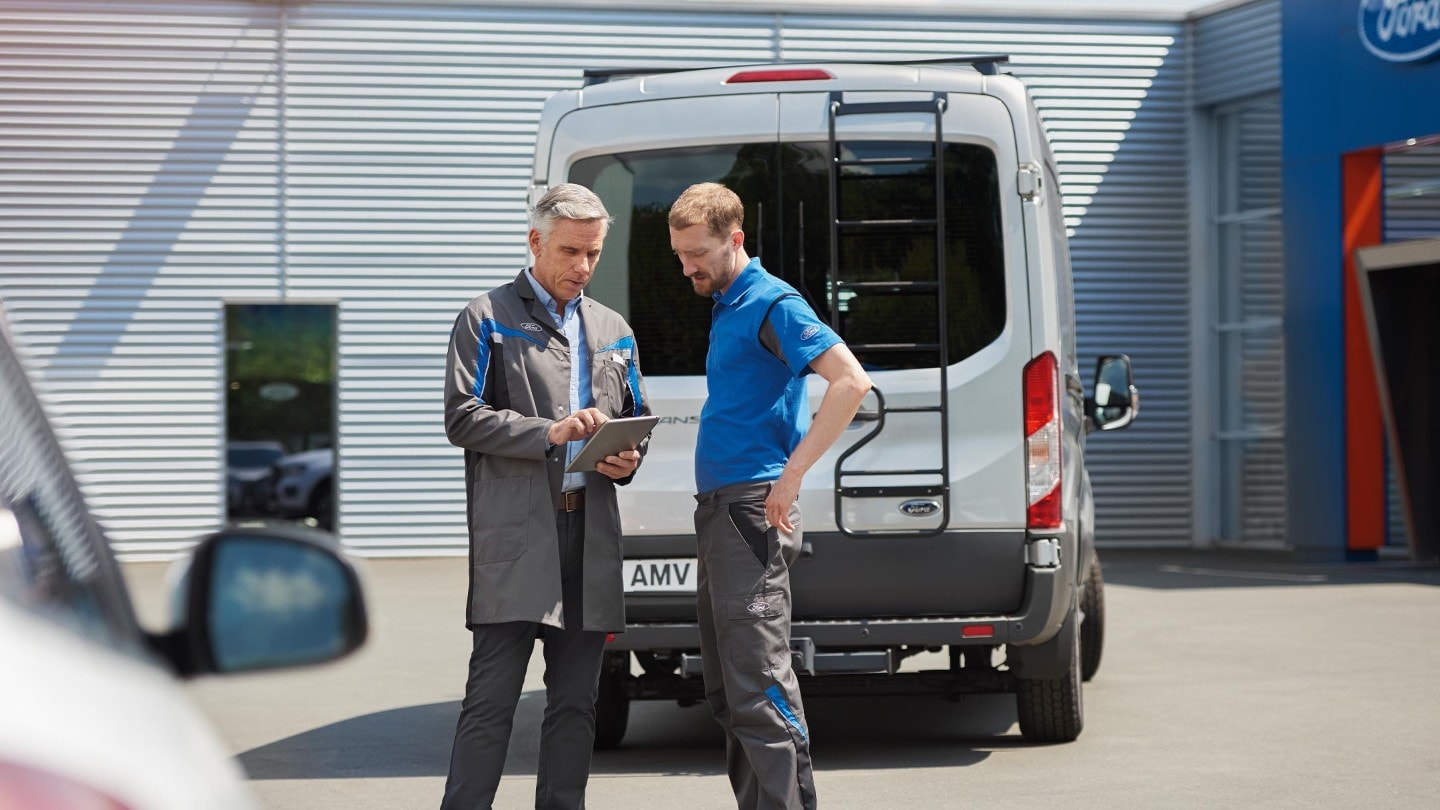  Personal de service și un proprietar Ford E-Transit discutând documentele din spatele E-Transit