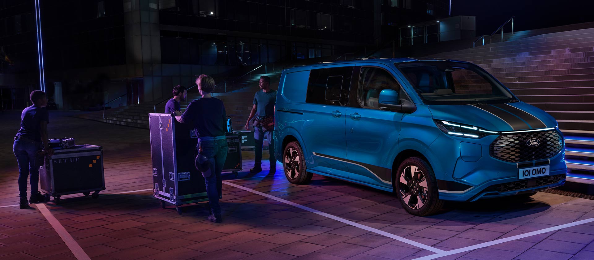Ford E-Transit Custom cu cabină dublă albastru pe timp de noapte.
