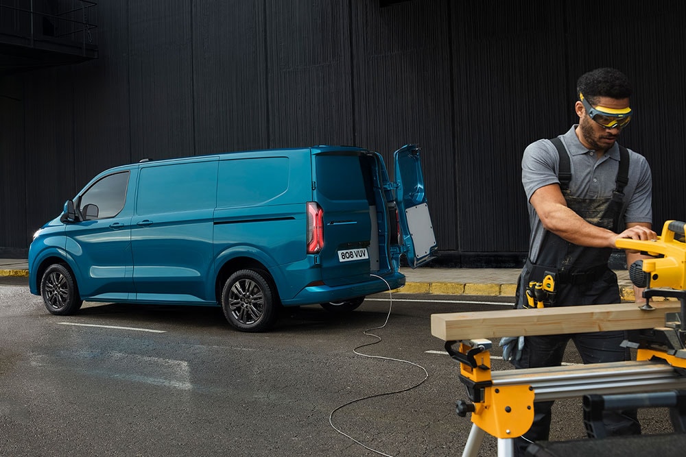 Furgon electric Ford E-Transit Custom albastru și o persoană care utilizează scule electrice.
