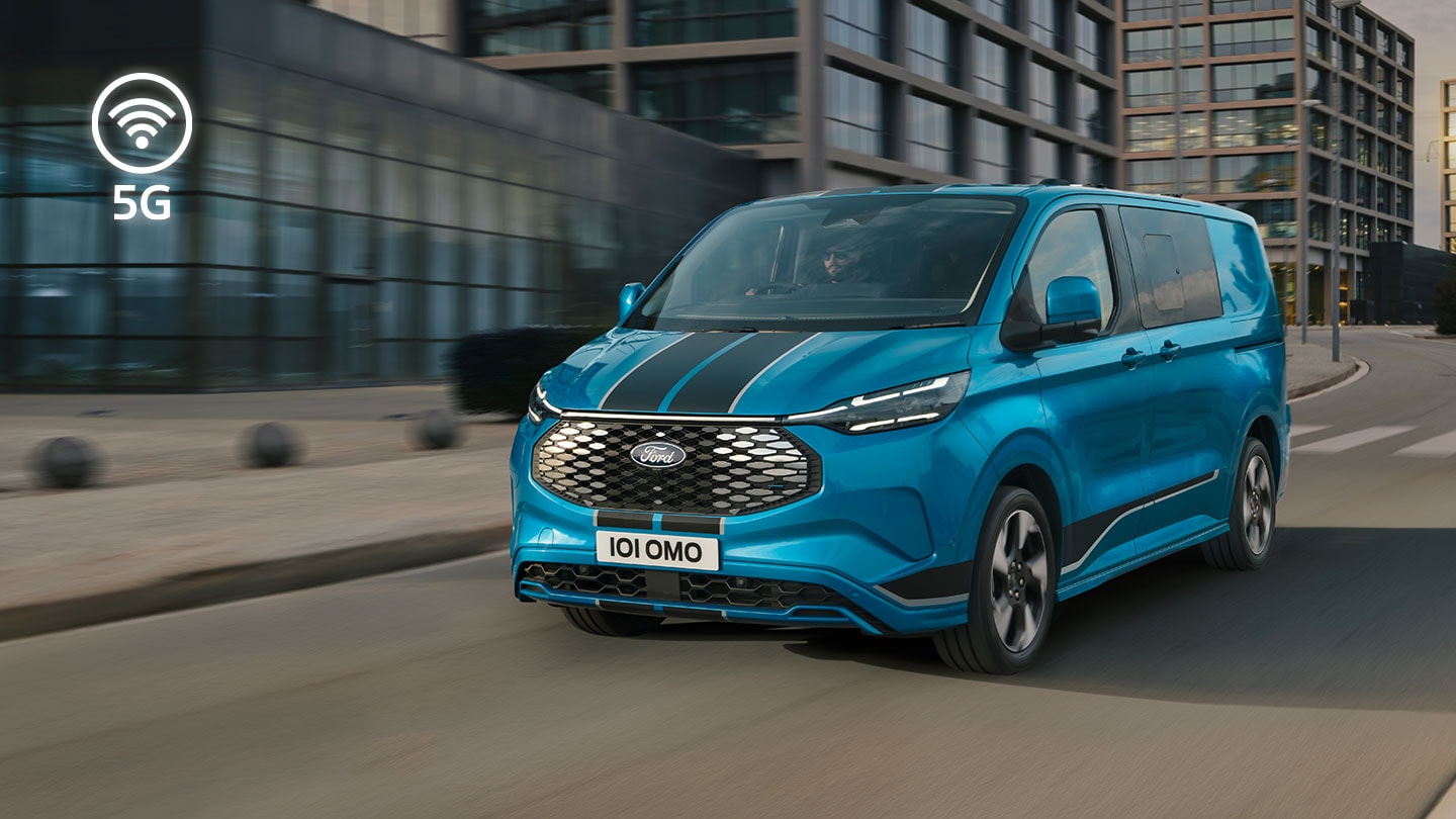 Furgon electric Ford E-Transit Custom albastru care se deplasează pe o stradă din oraș.