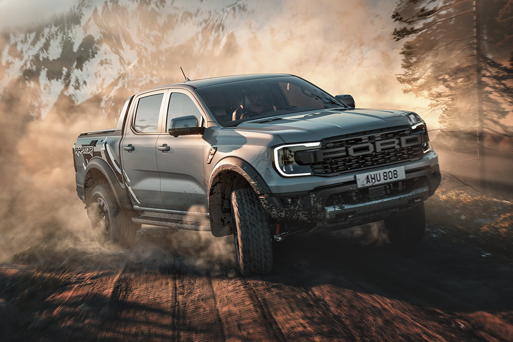 Ford Ranger Raptor în modul „Baja”, pe un drum de pământ, cu un peisaj montan în fundal.