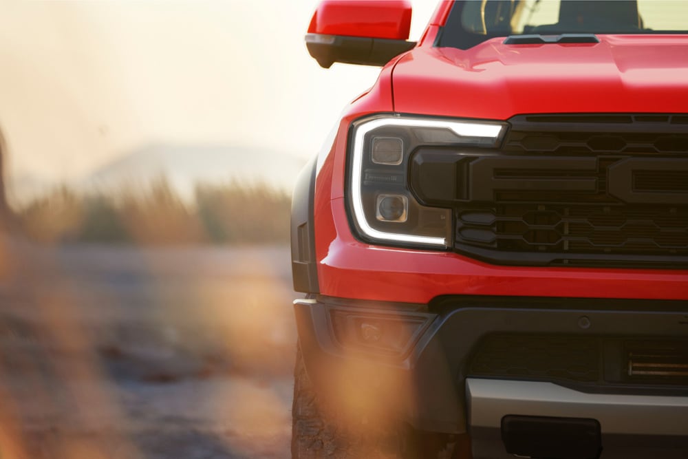 Prim-planul grilei frontale a unui Ford Ranger Raptor roșu.