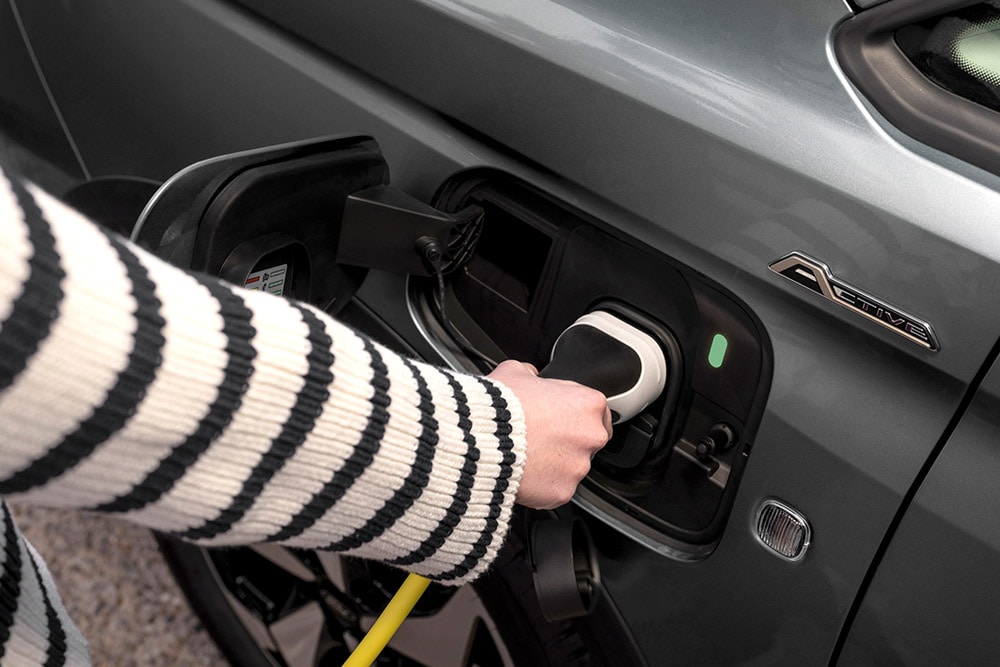 O persoană care conectează un cablu de încărcare la un Ford Transit Connect plug-in hibrid.