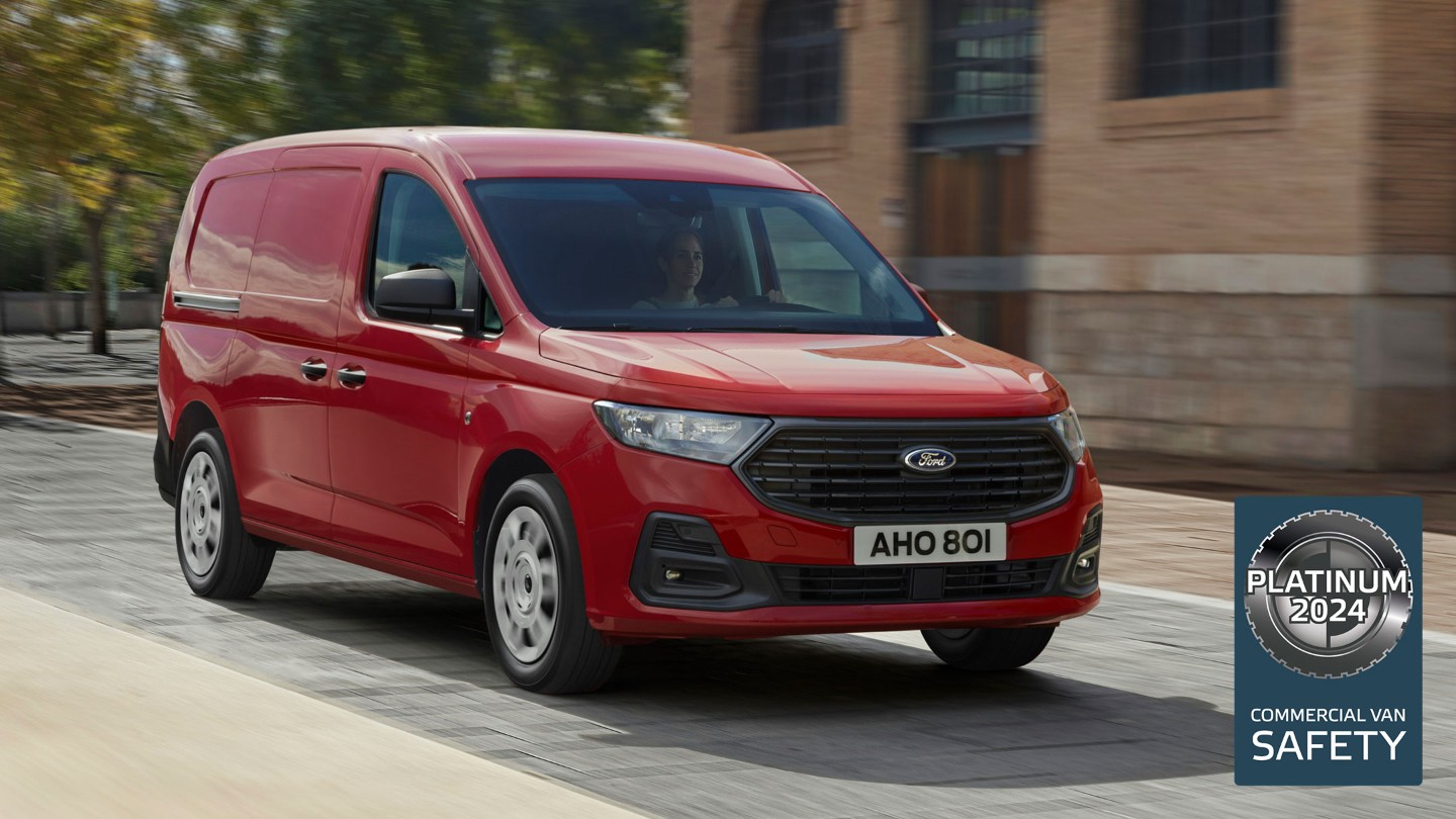 Noul Ford Transit Connect Trend în culoarea Maple Red merge pe o stradă, prezentând  grila frontală și farurile automate.