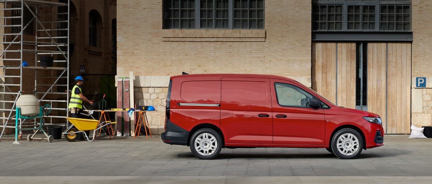 Noul Ford Transit Connect în culoarea Maple Red este parcat pe un șantier, prezentând ușa laterală de încărcare.
