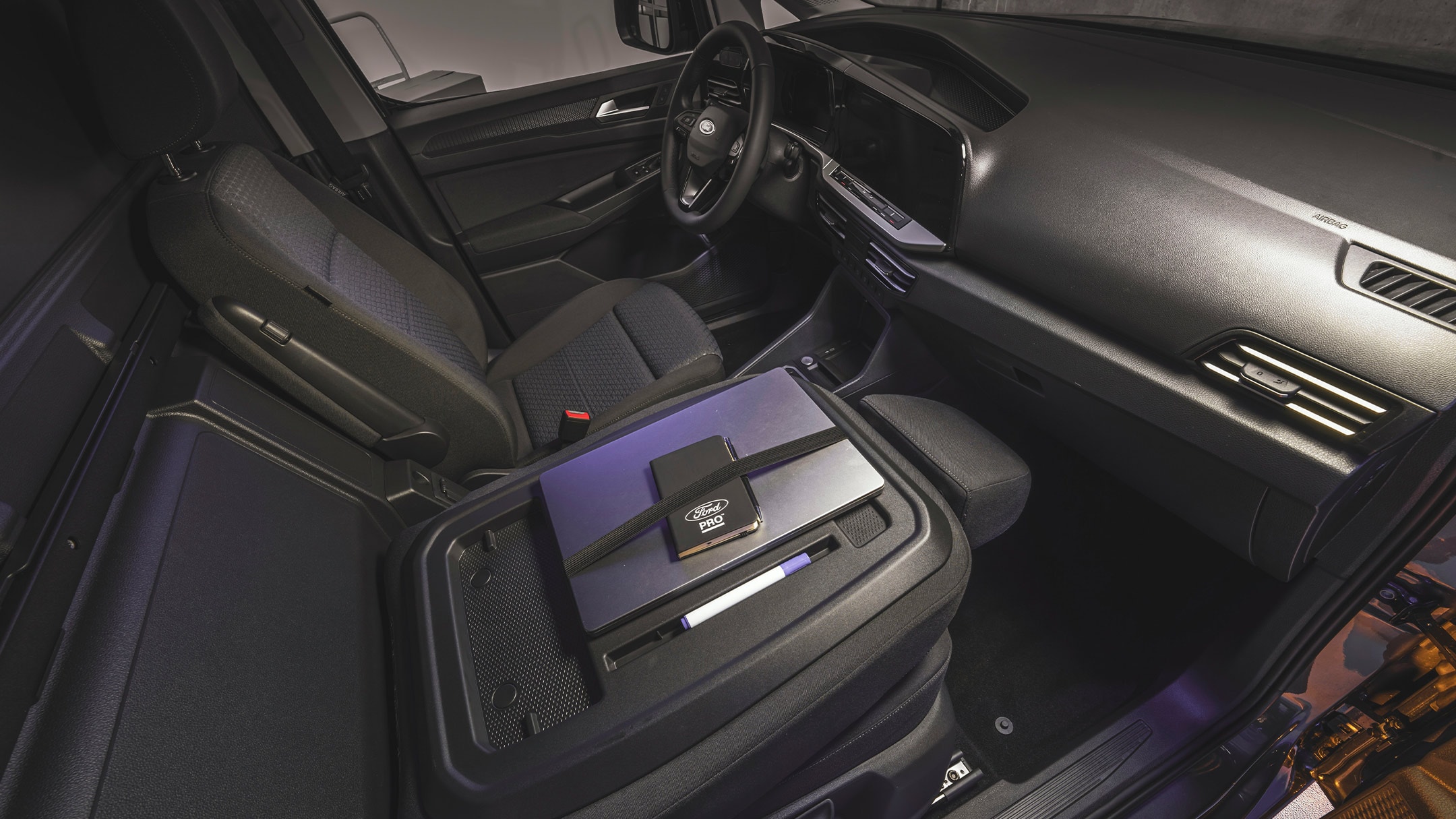 Un laptop și un notebook Ford Pro se află pe masa de lucru a unui nou model Ford Transit Connect.