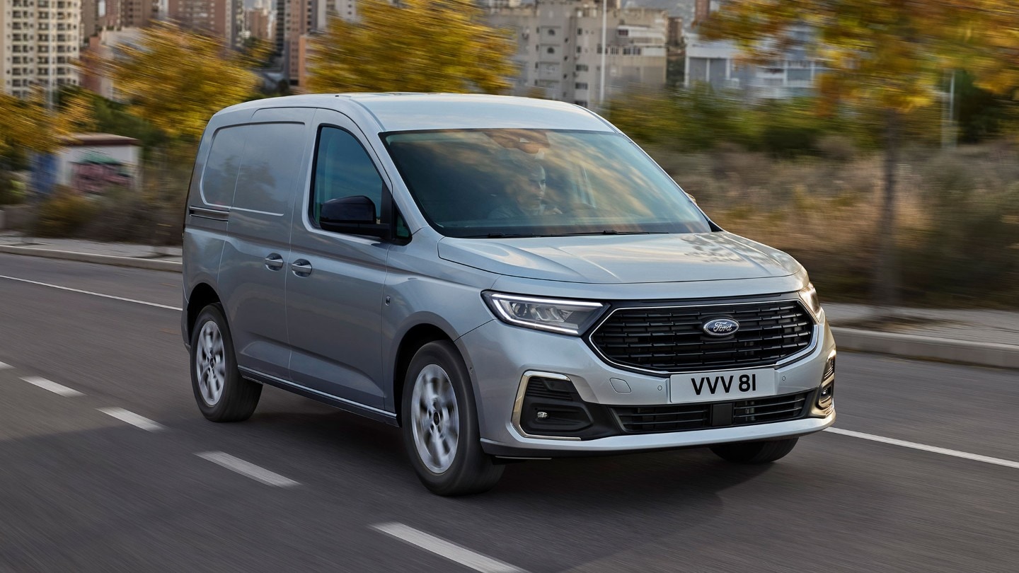Noul Ford Transit Connect Limited în culoarea Stardust Silver care merge pe un drum, prezentând contururi exterioare cromate și faruri automate.