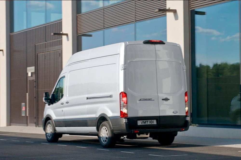Spatele unei furgonete Ford Transit argintii parcată pe o stradă din oraș. 