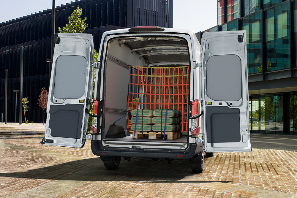 Ford Transit cu cabină dublă, cu ușile din spate deschise și încărcătură în interior.