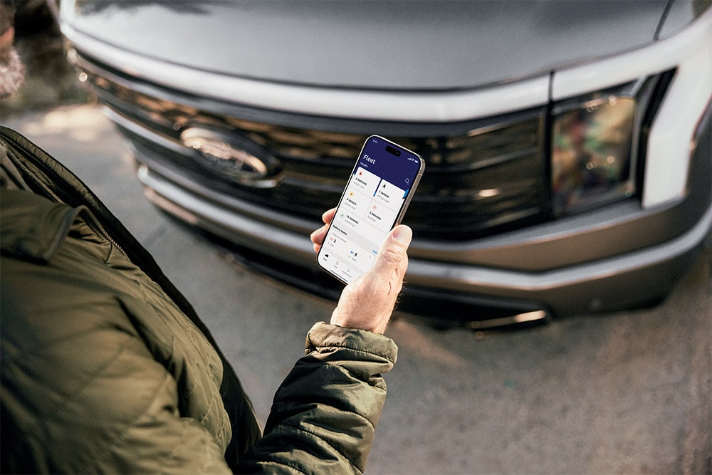 Un bărbat care își verifică smartphone-ul în fața unui Ford Ranger.