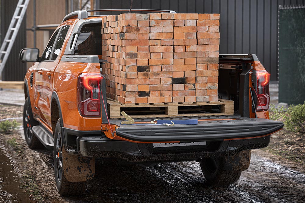 Vedere din spate a unui Ford Ranger culoare Code Orange, o grămadă de cărămizi încărcate pe patul mașinii.