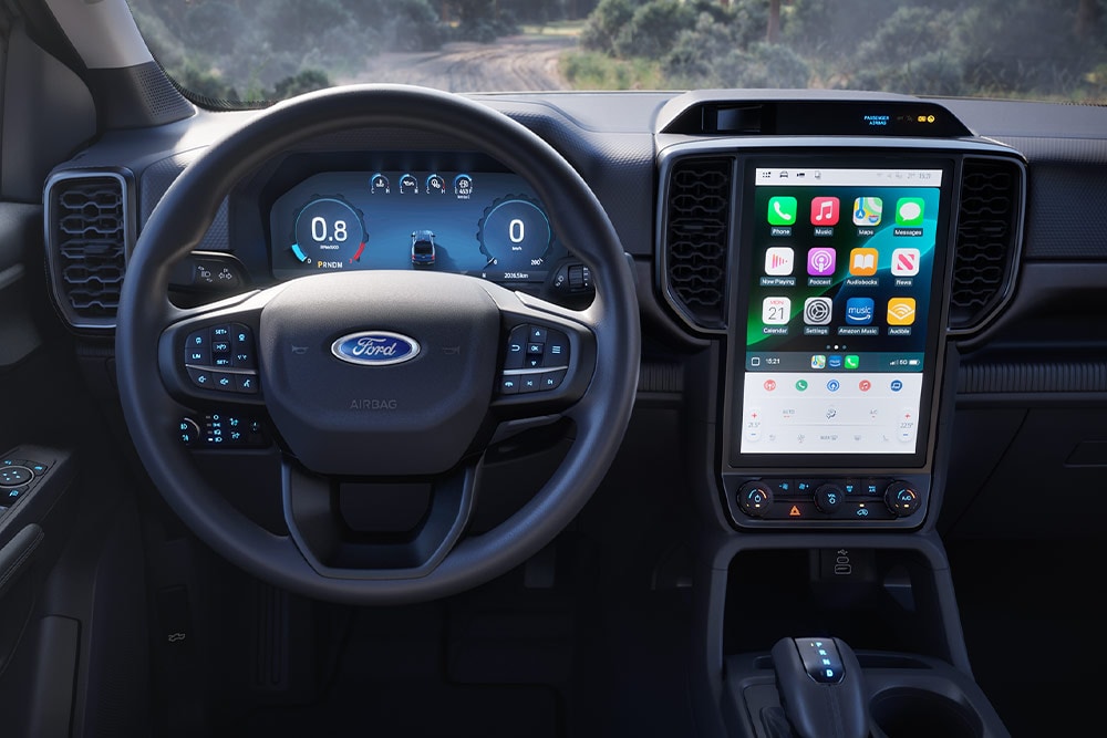 Vedere interioară a unui Ford Ranger cu cabină extinsă, concentrându-se pe volan, tabloul de bord și ecranul de infotainment.