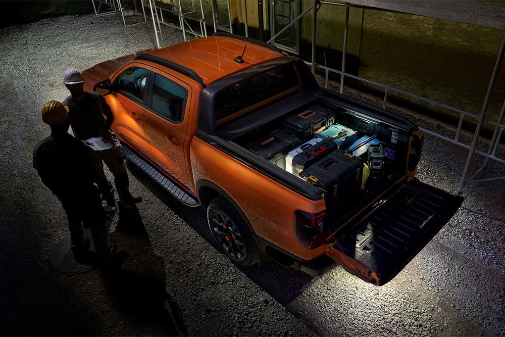 Vedere aeriană a Ford Ranger Wildtrak portocaliu pe timp de noapte, cu iluminare exterioară a zonei.
