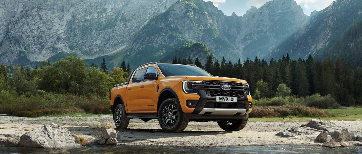 Noul Ford Wildtrak parcat lângă munți, vedere frontală 3/4